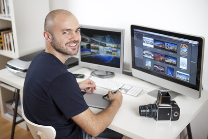 Jeune homme photographe retouchant ses photos sur son ordinateur